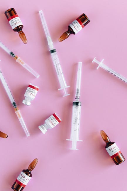 Vaccine vials and syringes on pink background